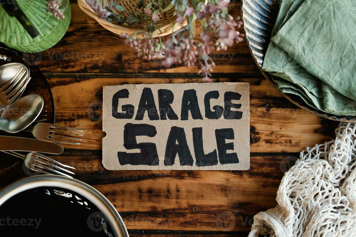 Garage sale sign and used items on wooden table. photo