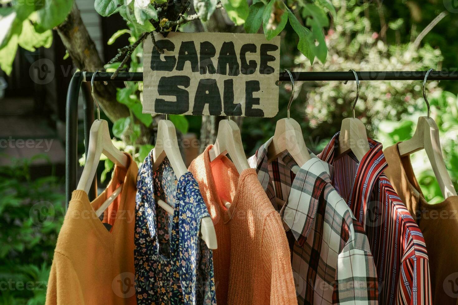 Garage sale, clothes for sale hanging on hanger outdoors. photo