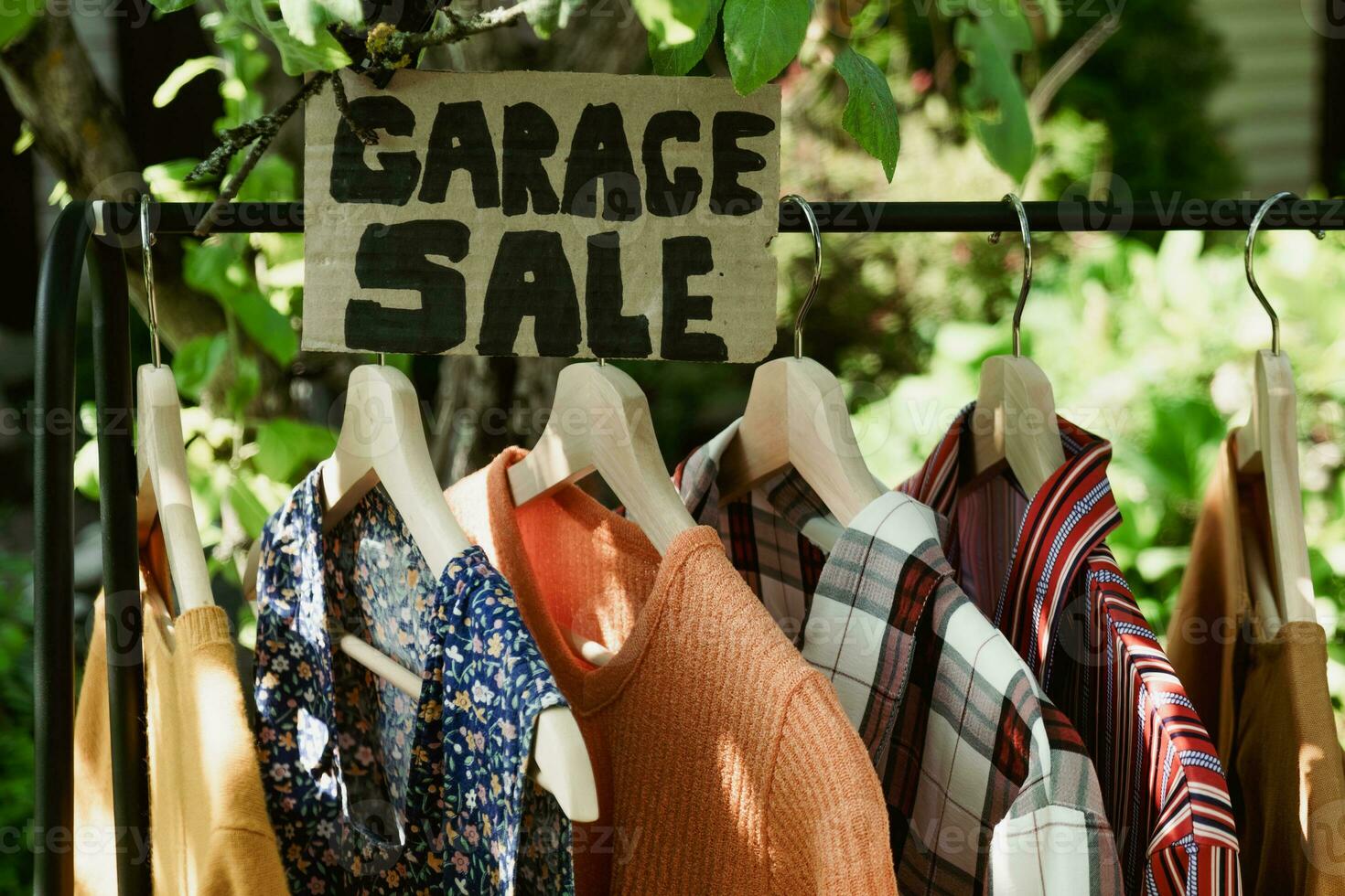 Garage sale, clothes for sale hanging on hanger outdoors. photo