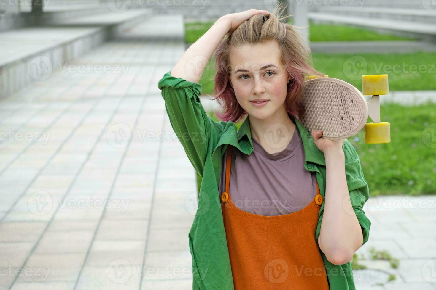 Beautiful skater young woman with skateboard outdoors. photo