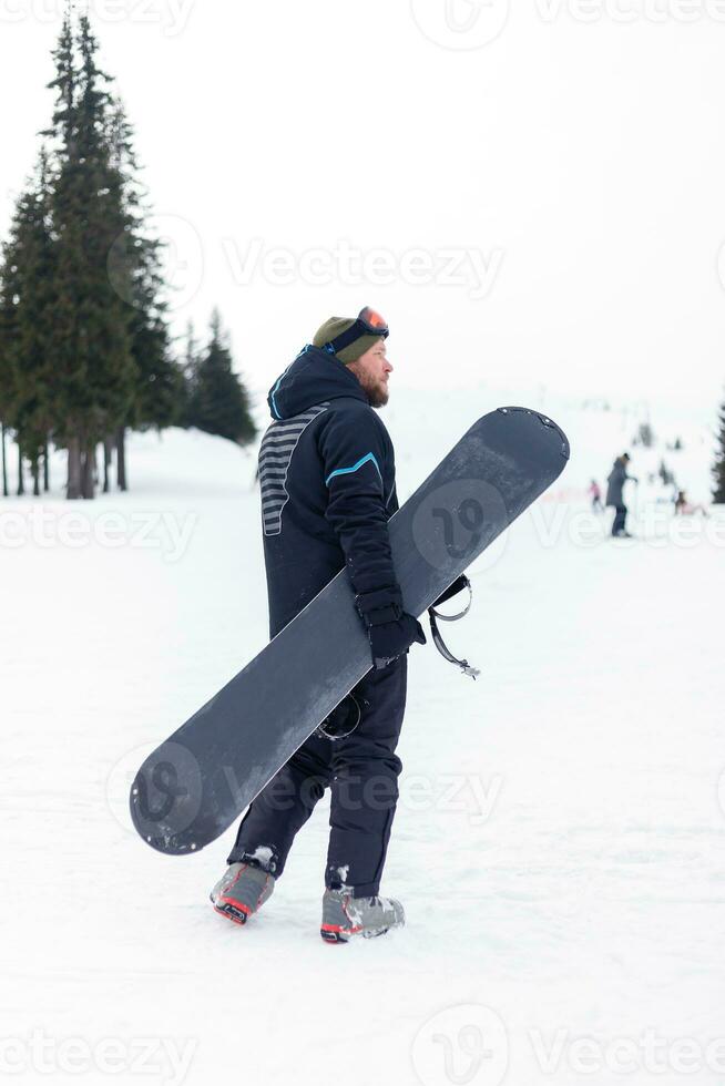 Snowboarder in helmet standing at the very top of a mountain photo