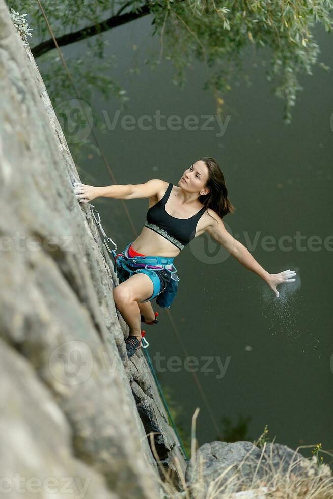 A girl climbs a rock. Woman engaged in extreme sport. photo