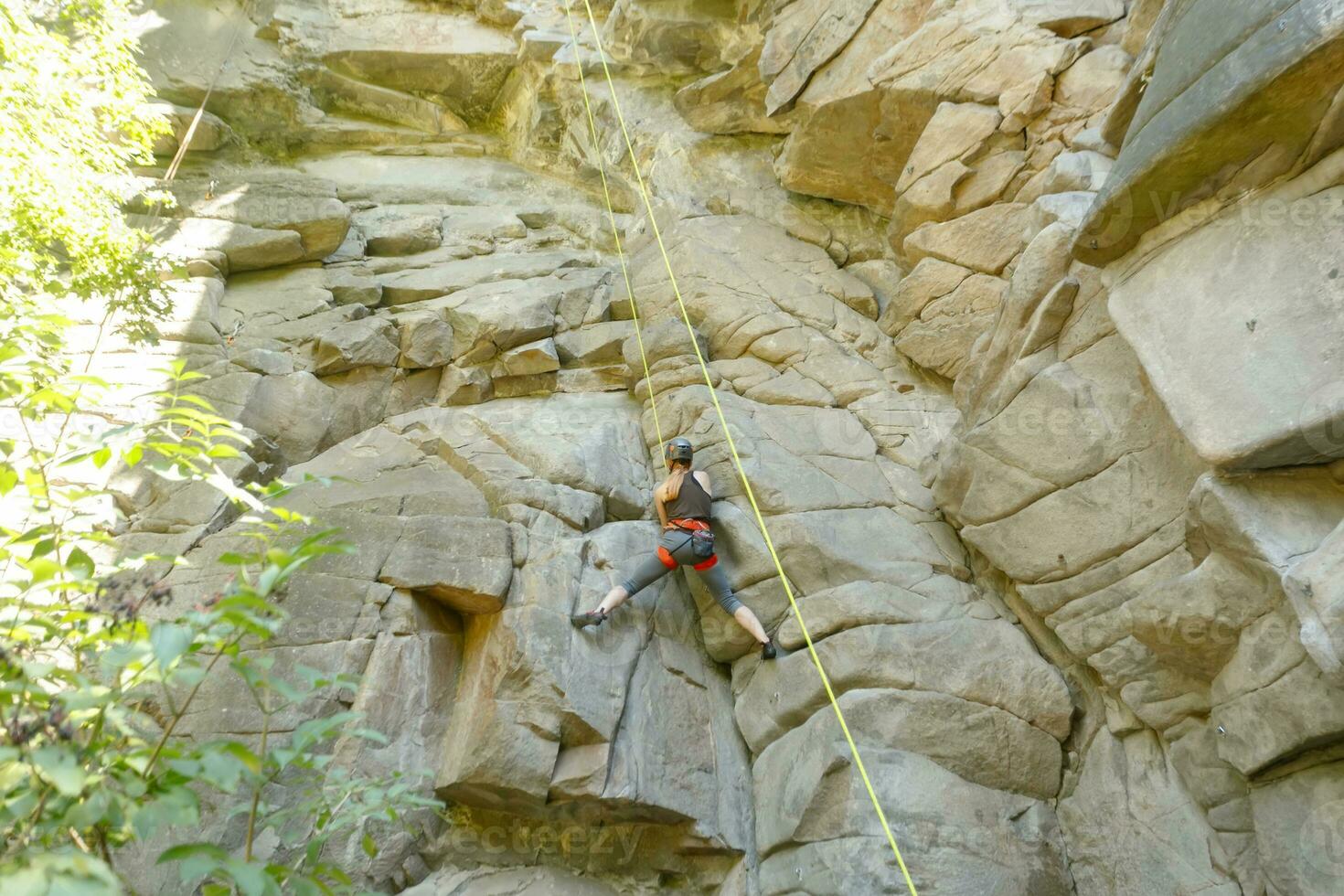 A girl climbs a rock. Woman engaged in extreme sport. photo