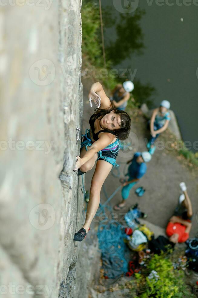 A girl climbs a rock. Woman engaged in extreme sport. photo