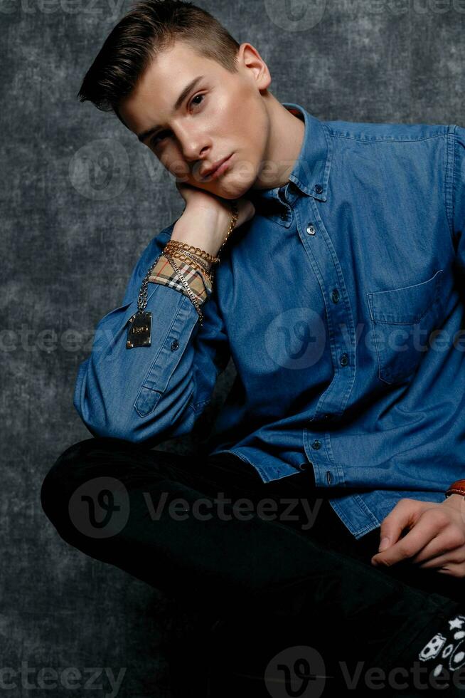 Man in denim shirt, arms on hips, gray background. photo