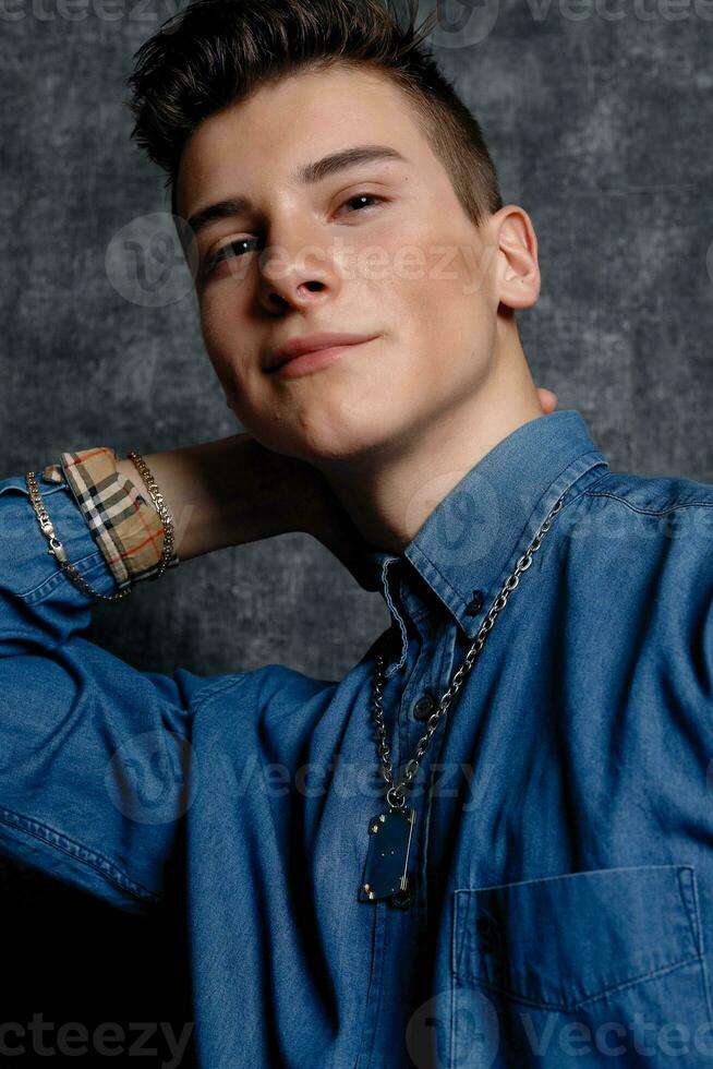 Man in denim shirt, arms on hips, gray background. photo