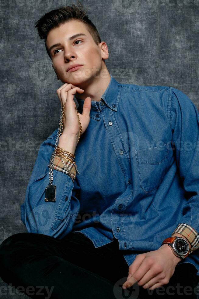 Man in denim shirt, arms on hips, gray background. photo