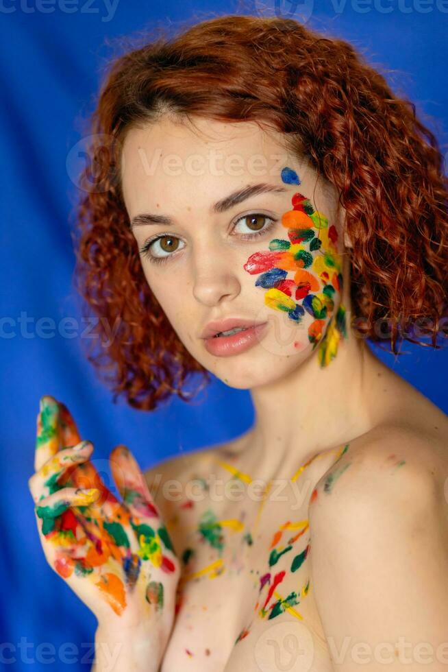 Close-up portrait of red curly haired woman Young cheerful soiled in paint. photo