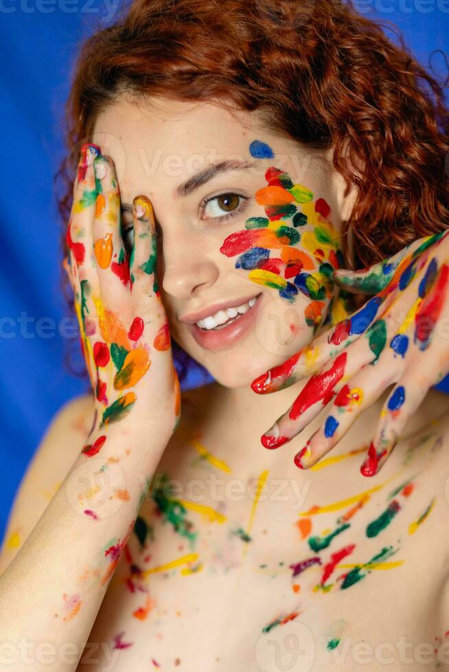 Close-up portrait of red curly haired woman Young cheerful soiled in paint. photo