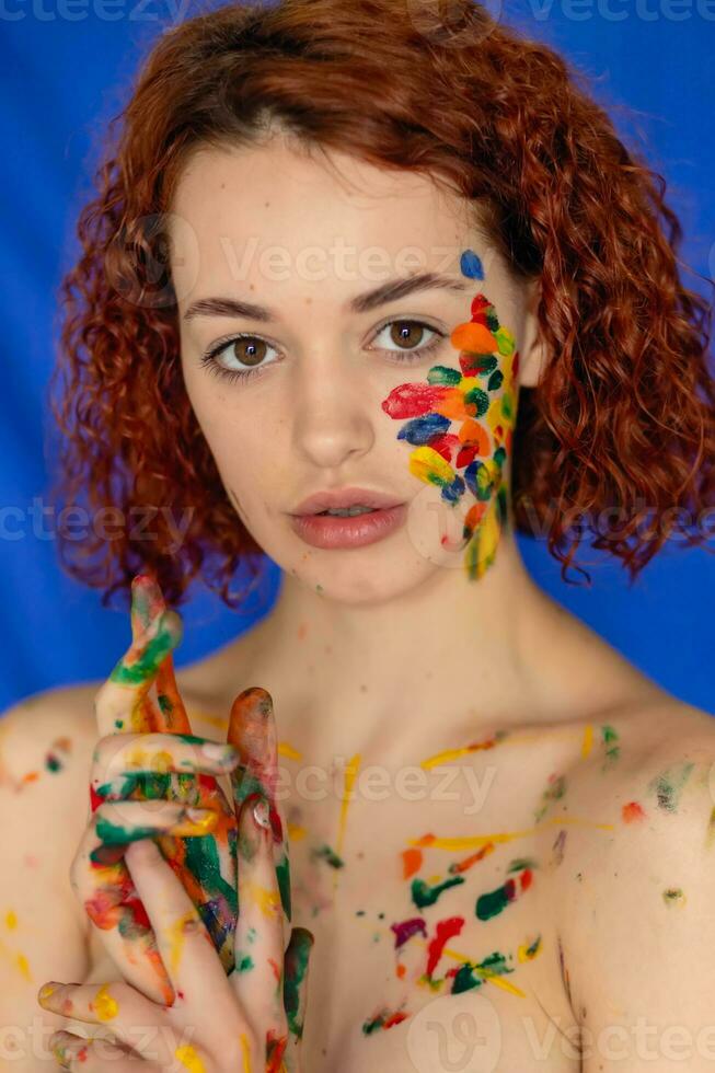 Close-up portrait of red curly haired woman Young cheerful soiled in paint. photo