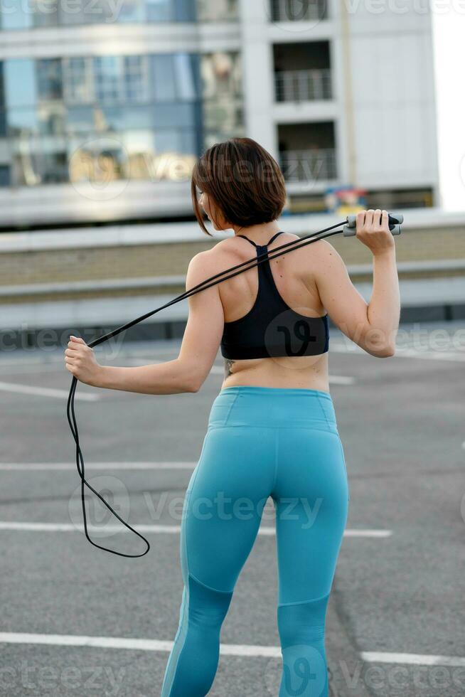 fuerte joven mujer extensión con salto a la comba. foto