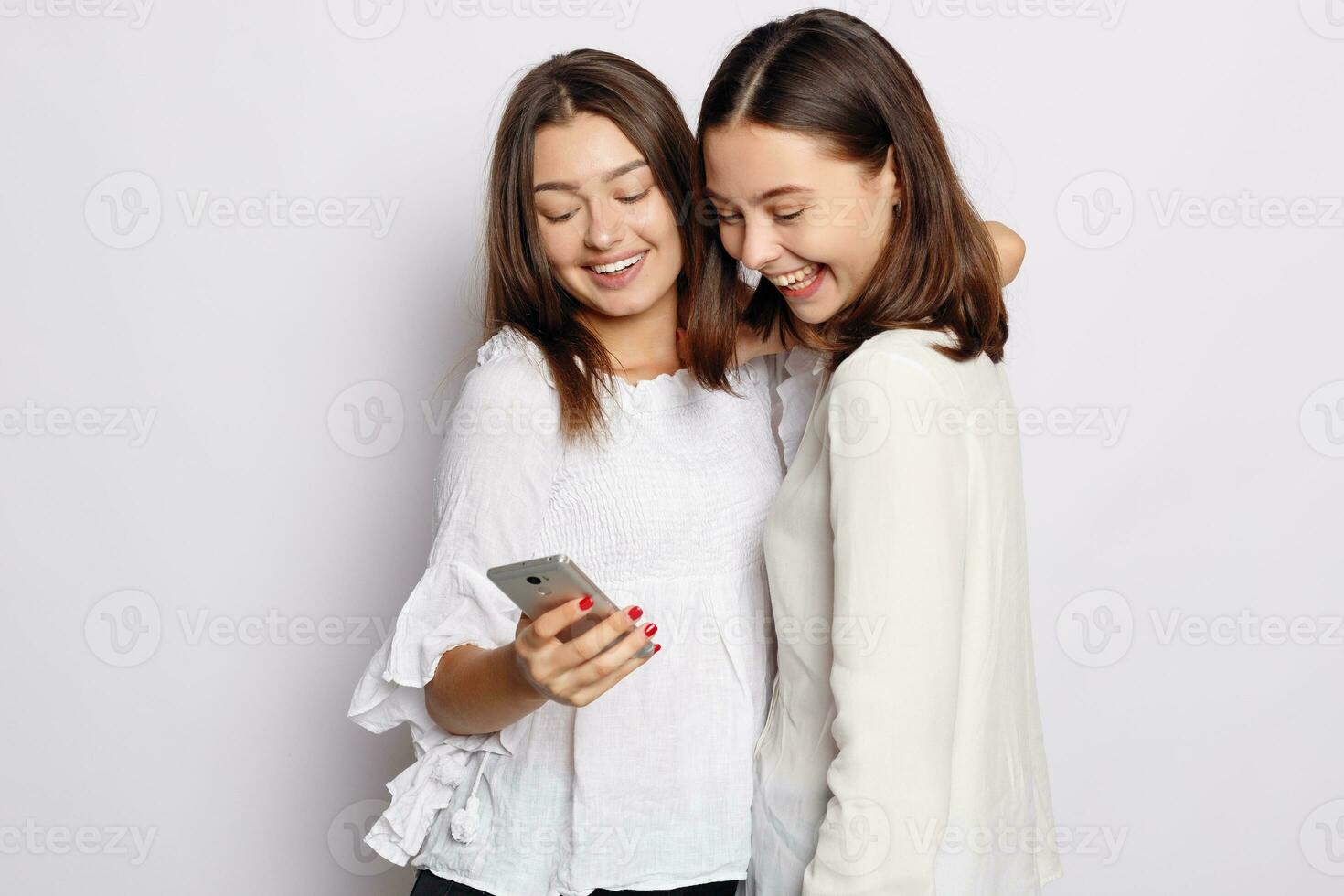 Happy smiling young woman showing photos on mobile phone