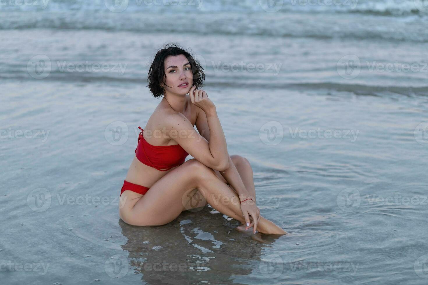 Sexy back of a beautiful woman in red bikini on sea background photo