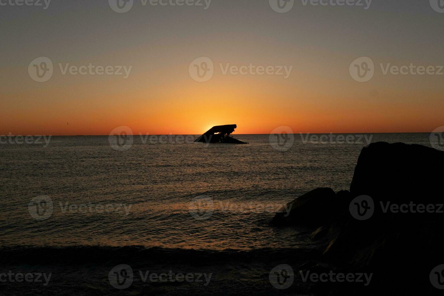 Sunset beach in Cape May New Jersey where you can get a great view of the sun going down across the ocean and the bay. The reflection of the sun on the water with the sunken ship looks so beautiful. photo