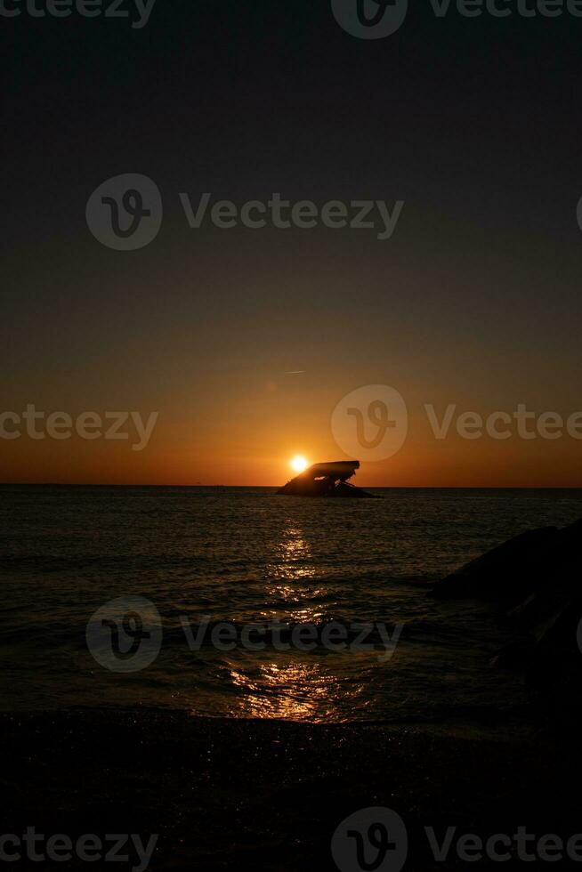 Sunset beach in Cape May New Jersey where you can get a great view of the sun going down across the ocean and the bay. The reflection of the sun on the water with the sunken ship looks so beautiful. photo