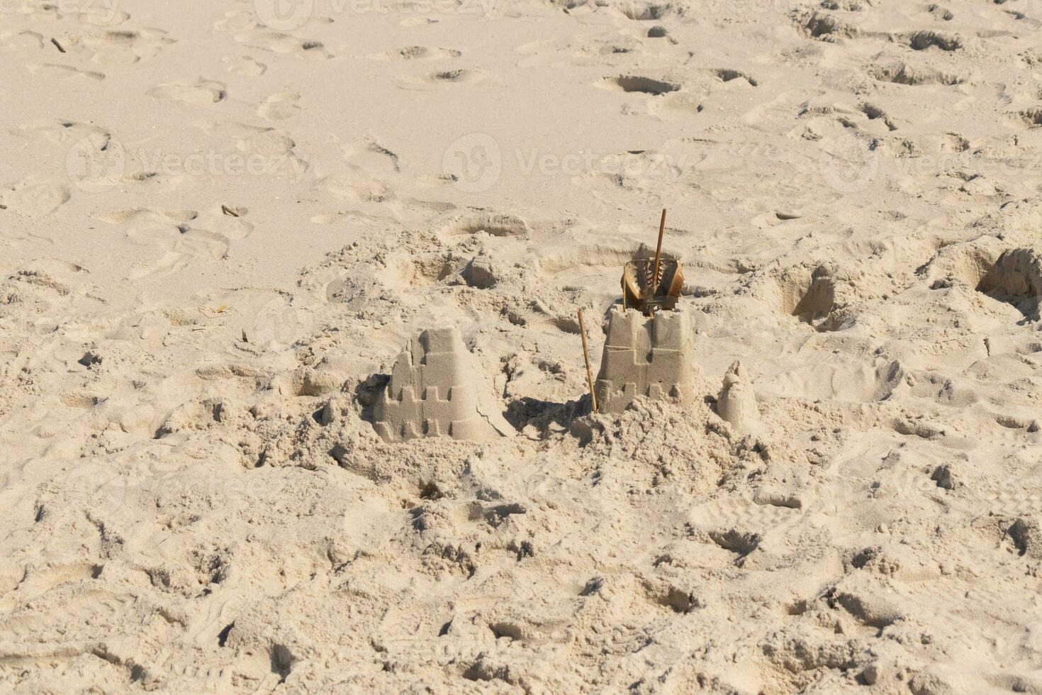 This beautiful brown sand castle is sitting here on this beach. The fort sits here with footprints all around. photo