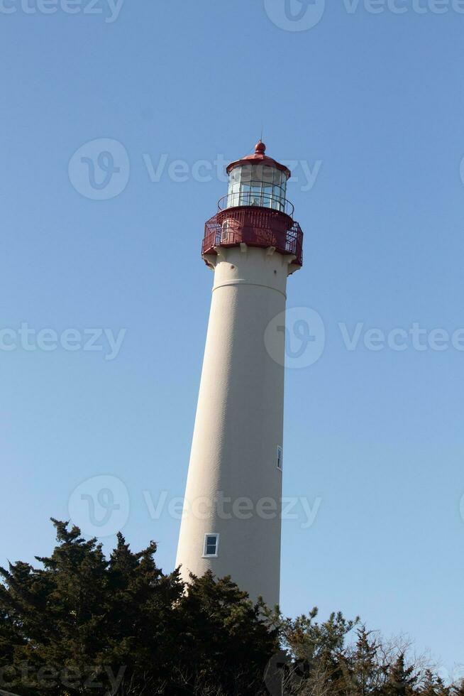 This is Cape May point lighthouse in New Jersey. I love the white look of its tower and the red top to it that stands out from so many. This beacon of hope helps people at sea to navigate. photo