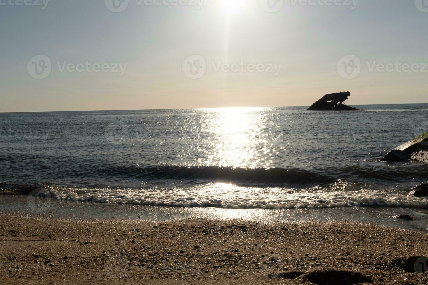 Sunset beach in Cape May New Jersey where you can get a great view of the sun going down across the ocean and the bay. The reflection of the sun on the water with the sunken ship looks so beautiful. photo