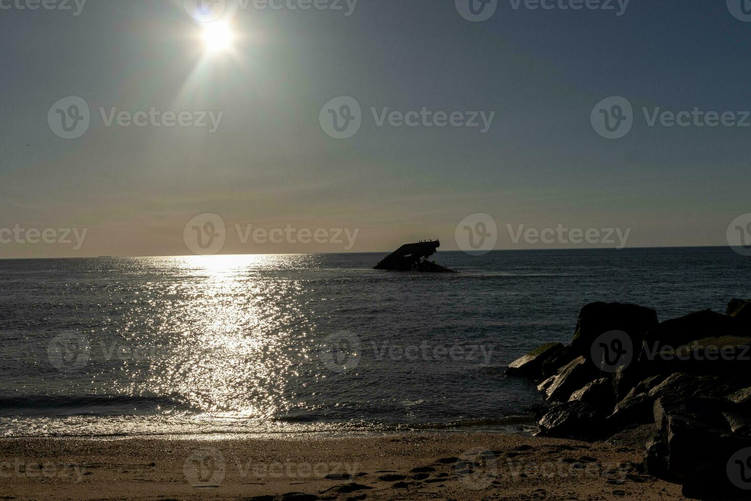 Sunset beach in Cape May New Jersey where you can get a great view of the sun going down across the ocean and the bay. The reflection of the sun on the water with the sunken ship looks so beautiful. photo