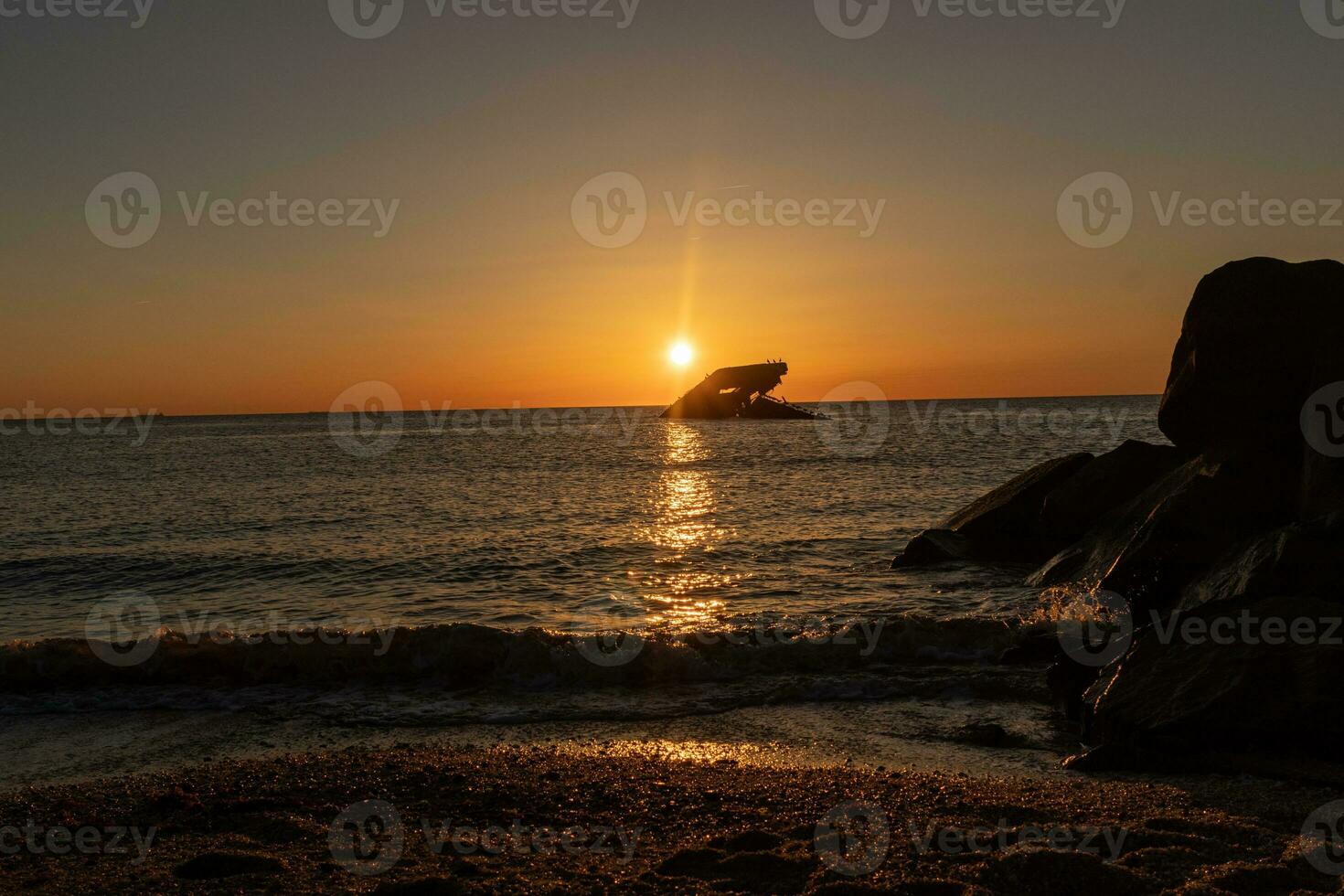 Sunset beach in Cape May New Jersey where you can get a great view of the sun going down across the ocean and the bay. The reflection of the sun on the water with the sunken ship looks so beautiful. photo