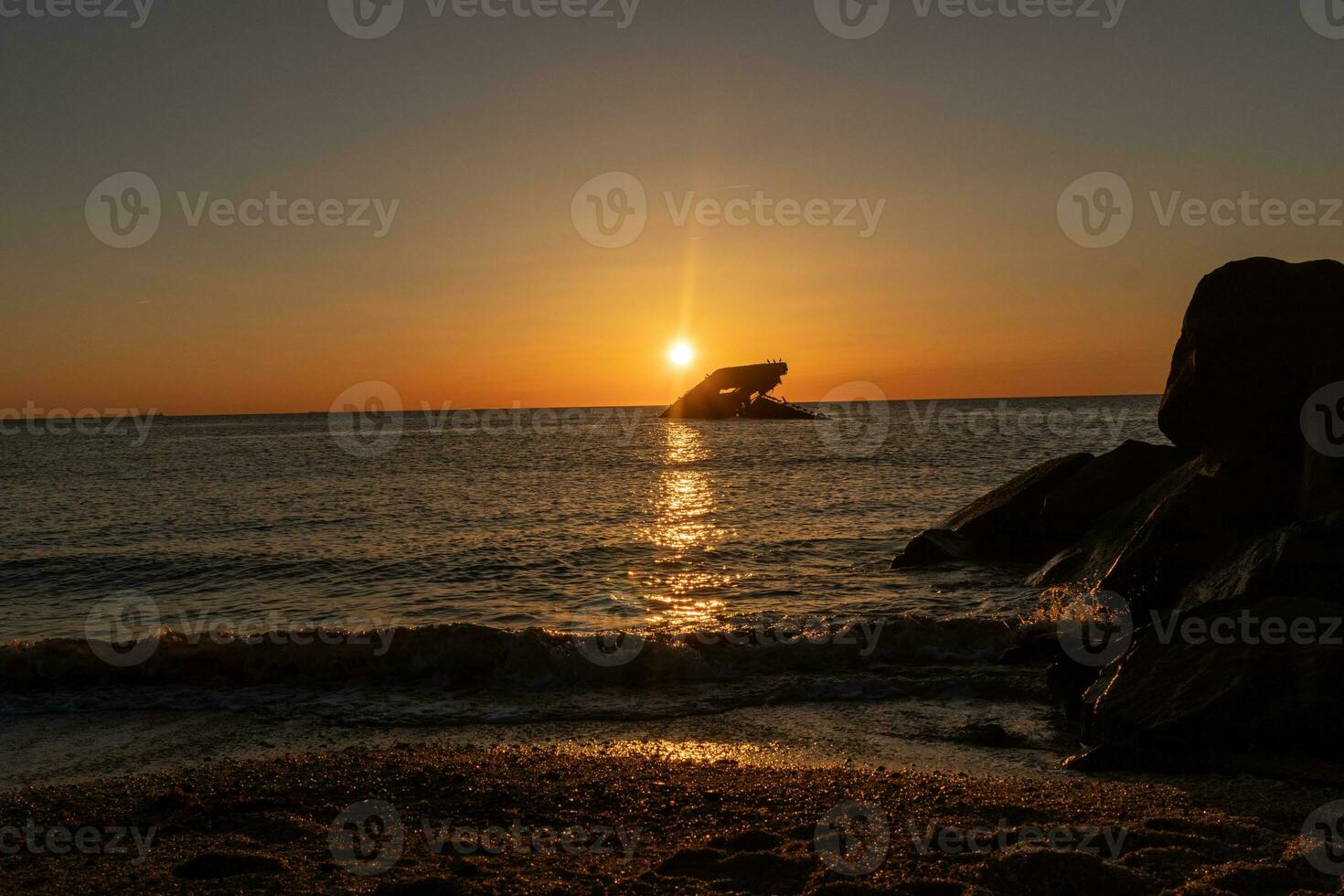 Sunset beach in Cape May New Jersey where you can get a great view of the sun going down across the ocean and the bay. The reflection of the sun on the water with the sunken ship looks so beautiful. photo