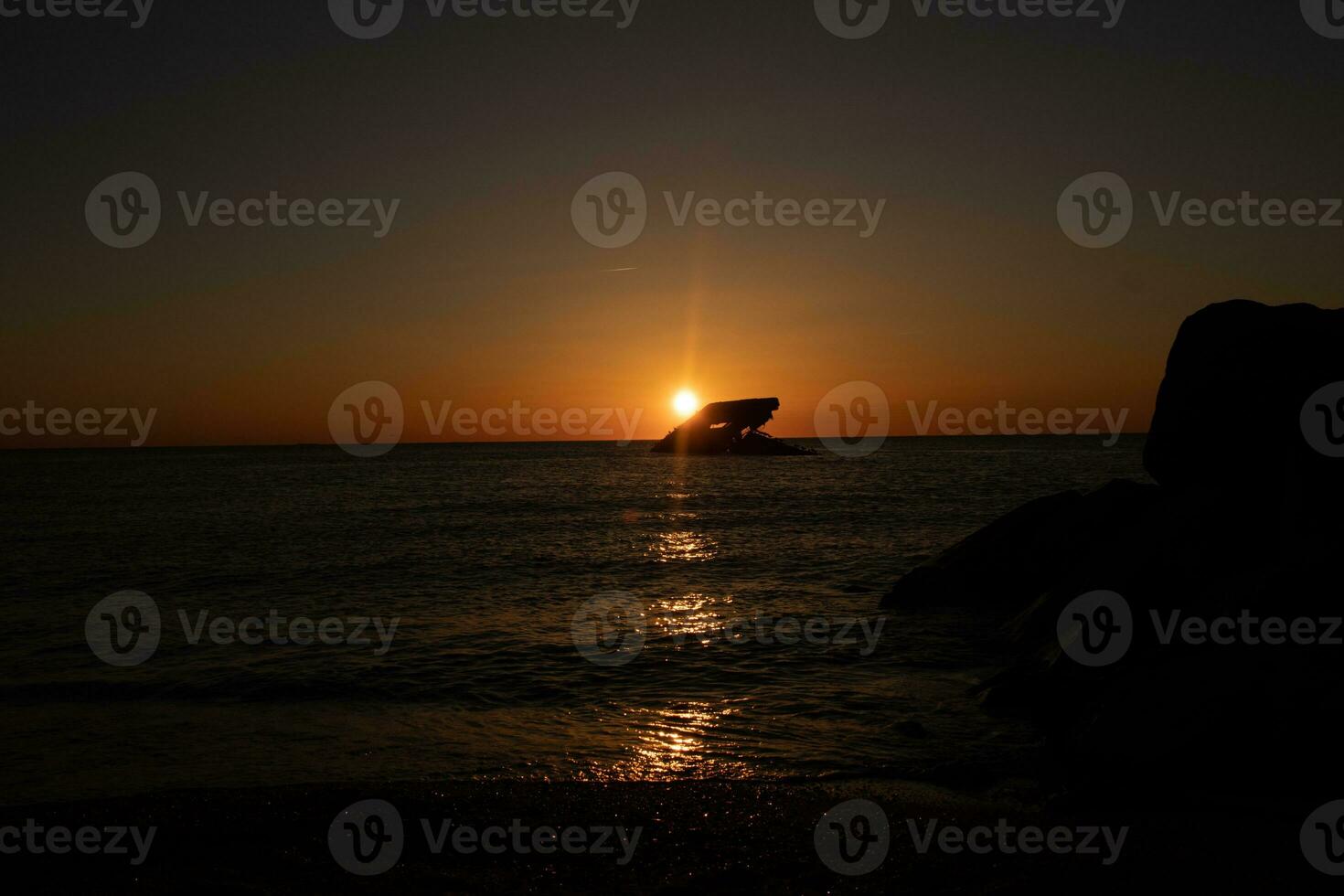 Sunset beach in Cape May New Jersey where you can get a great view of the sun going down across the ocean and the bay. The reflection of the sun on the water with the sunken ship looks so beautiful. photo