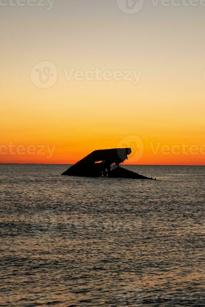 Sunset beach in Cape May New Jersey where you can get a great view of the sun going down across the ocean and the bay. The reflection of the sun on the water with the sunken ship looks so beautiful. photo
