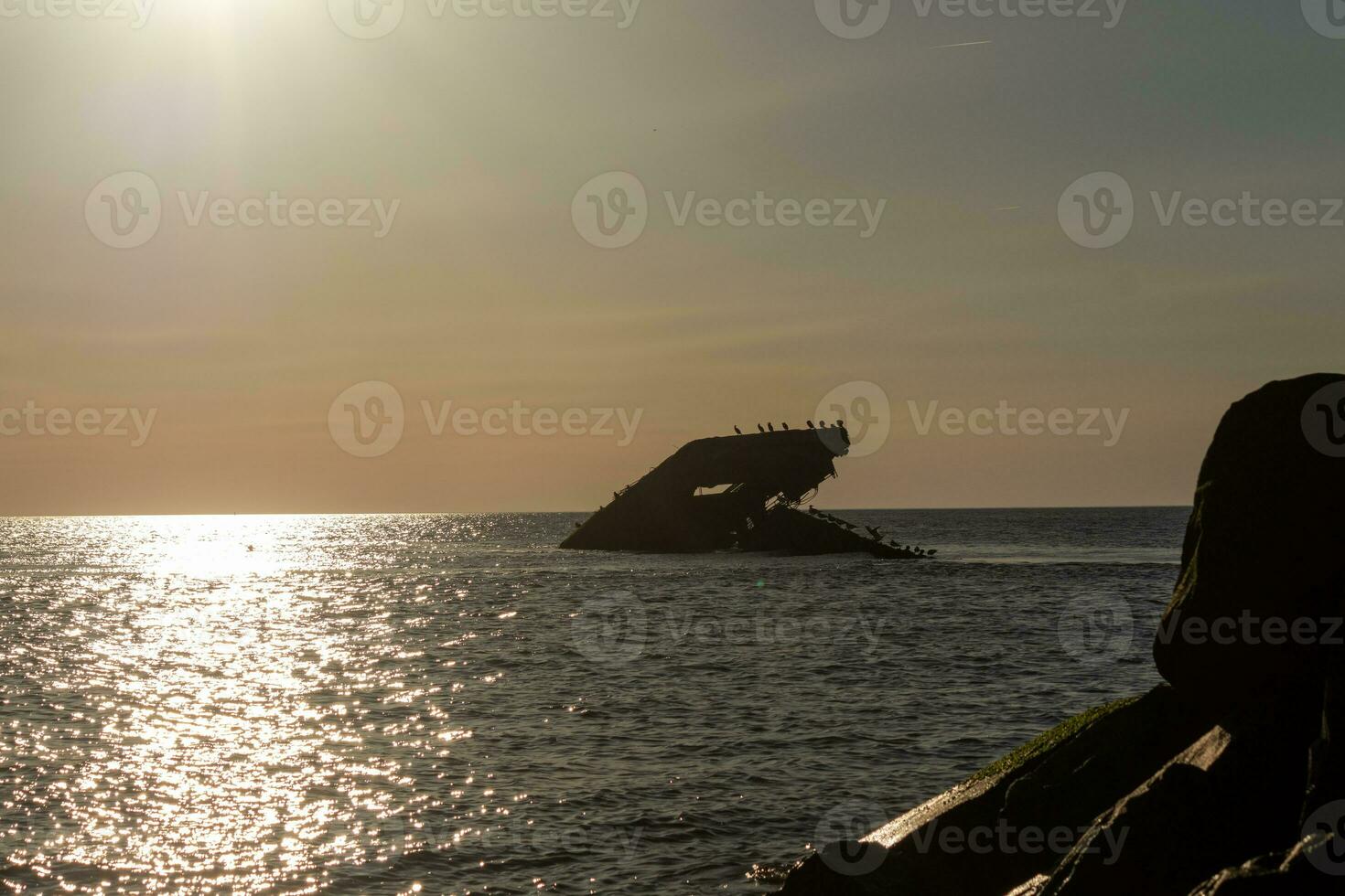 Sunset beach in Cape May New Jersey where you can get a great view of the sun going down across the ocean and the bay. The reflection of the sun on the water with the sunken ship looks so beautiful. photo