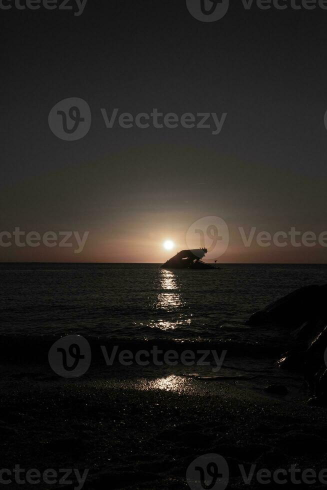 Sunset beach in Cape May New Jersey where you can get a great view of the sun going down across the ocean and the bay. The reflection of the sun on the water with the sunken ship looks so beautiful. photo