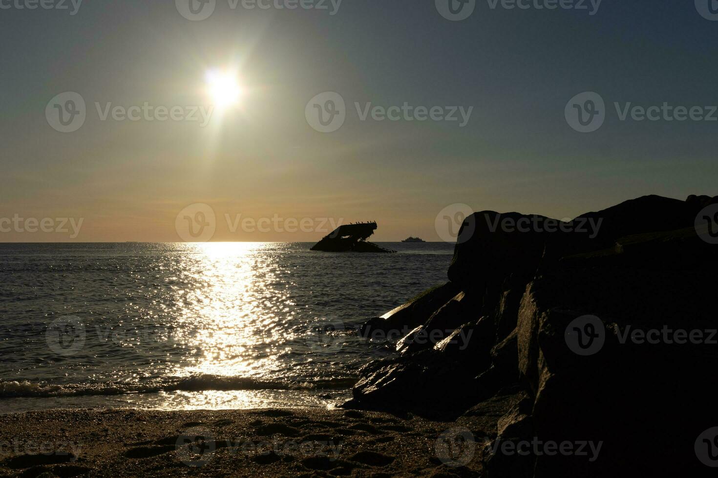 Sunset beach in Cape May New Jersey where you can get a great view of the sun going down across the ocean and the bay. The reflection of the sun on the water with the sunken ship looks so beautiful. photo