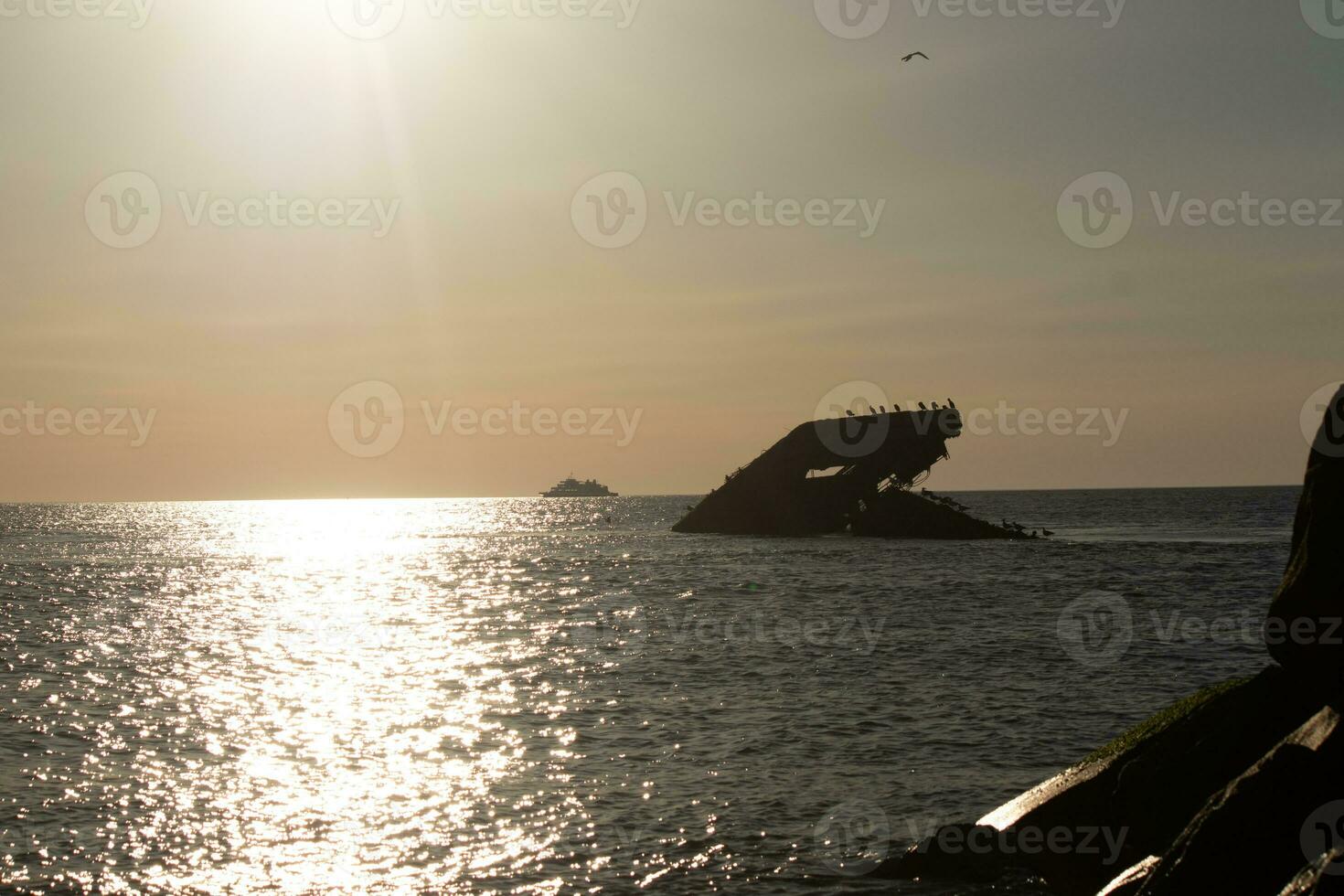 Sunset beach in Cape May New Jersey where you can get a great view of the sun going down across the ocean and the bay. The reflection of the sun on the water with the sunken ship looks so beautiful. photo