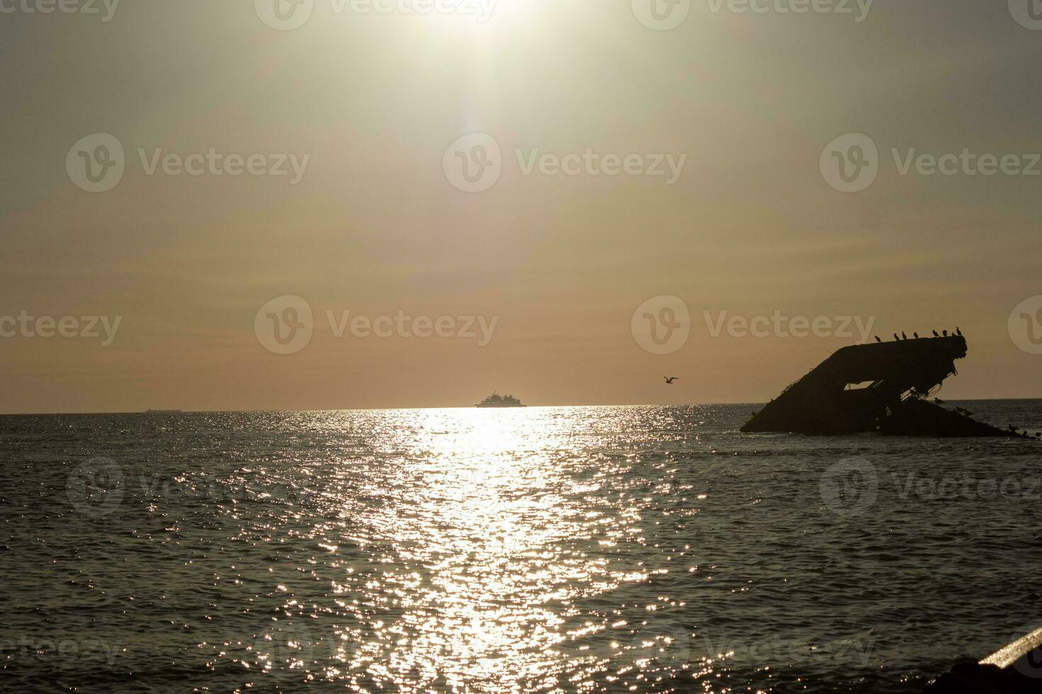 Sunset beach in Cape May New Jersey where you can get a great view of the sun going down across the ocean and the bay. The reflection of the sun on the water with the sunken ship looks so beautiful. photo