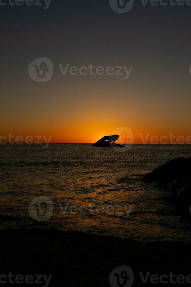 Sunset beach in Cape May New Jersey where you can get a great view of the sun going down across the ocean and the bay. The reflection of the sun on the water with the sunken ship looks so beautiful. photo