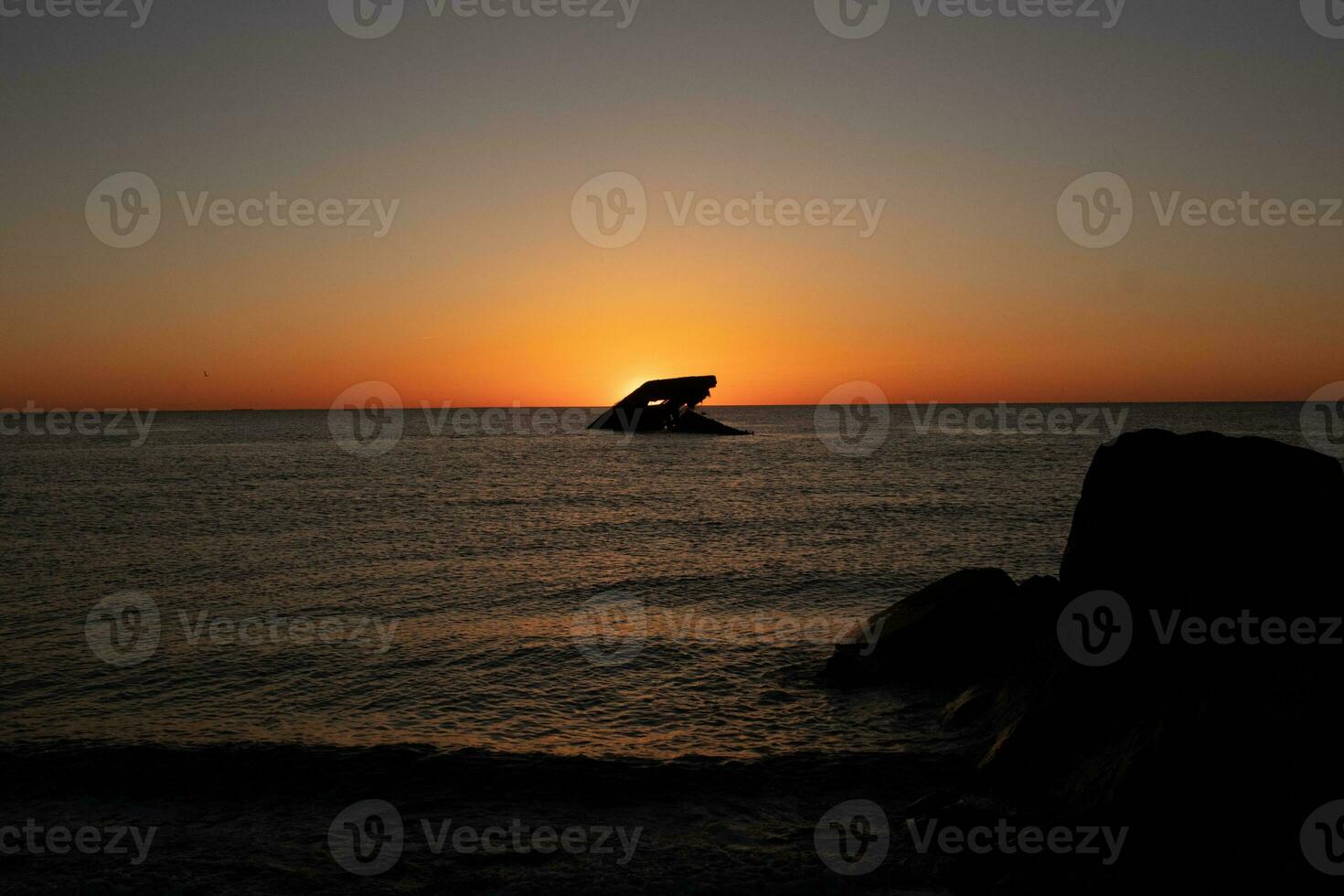 Sunset beach in Cape May New Jersey where you can get a great view of the sun going down across the ocean and the bay. The reflection of the sun on the water with the sunken ship looks so beautiful. photo