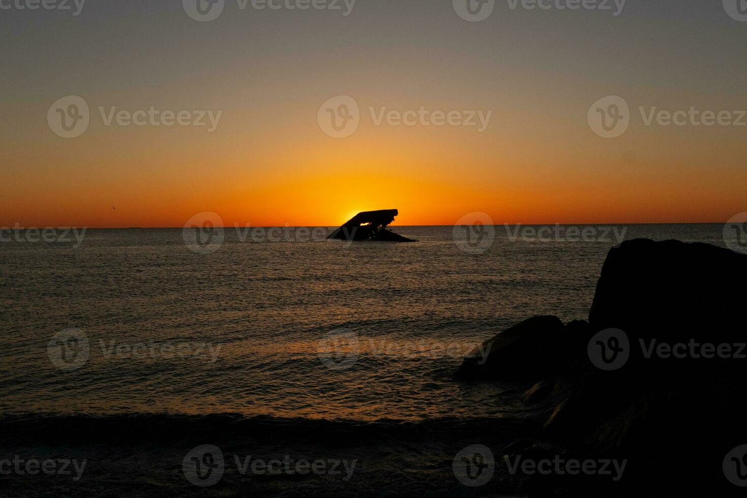 Sunset beach in Cape May New Jersey where you can get a great view of the sun going down across the ocean and the bay. The reflection of the sun on the water with the sunken ship looks so beautiful. photo