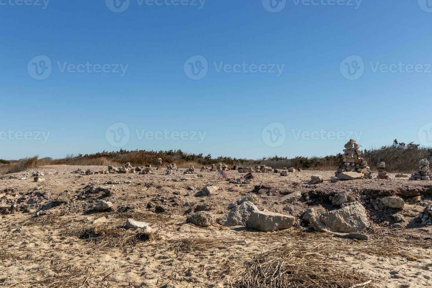 This rocky beach was at Sunset Beach in Cape May New Jersey. This beach is iconic for all the pebbles and rocks that are on it. The sand dunes in the back really add to this image. photo