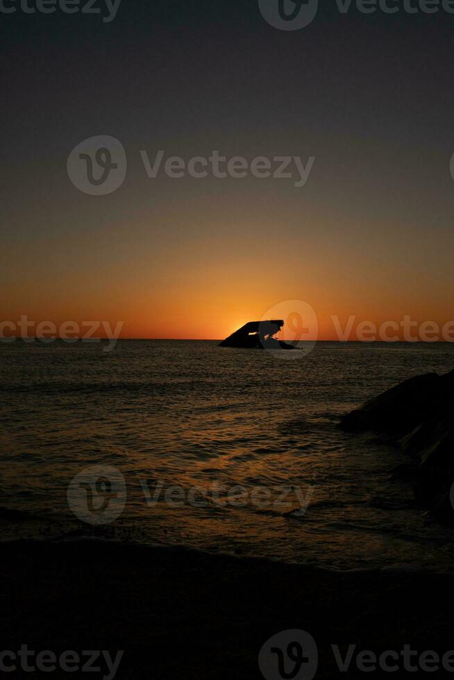 Sunset beach in Cape May New Jersey where you can get a great view of the sun going down across the ocean and the bay. The reflection of the sun on the water with the sunken ship looks so beautiful. photo