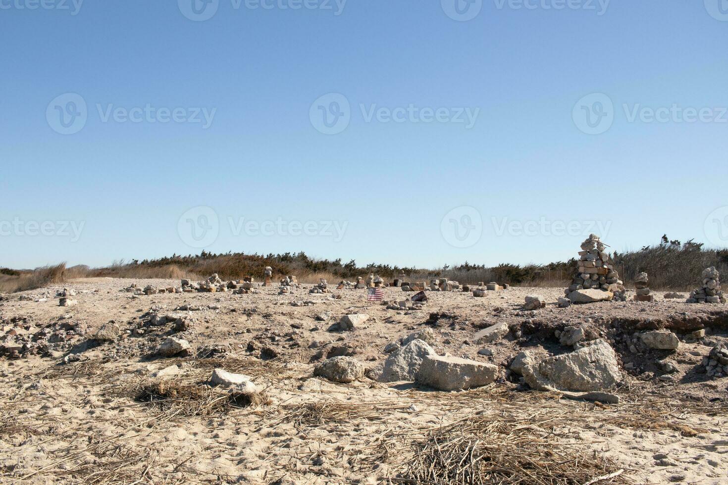 This rocky beach was at Sunset Beach in Cape May New Jersey. This beach is iconic for all the pebbles and rocks that are on it. The sand dunes in the back really add to this image. photo