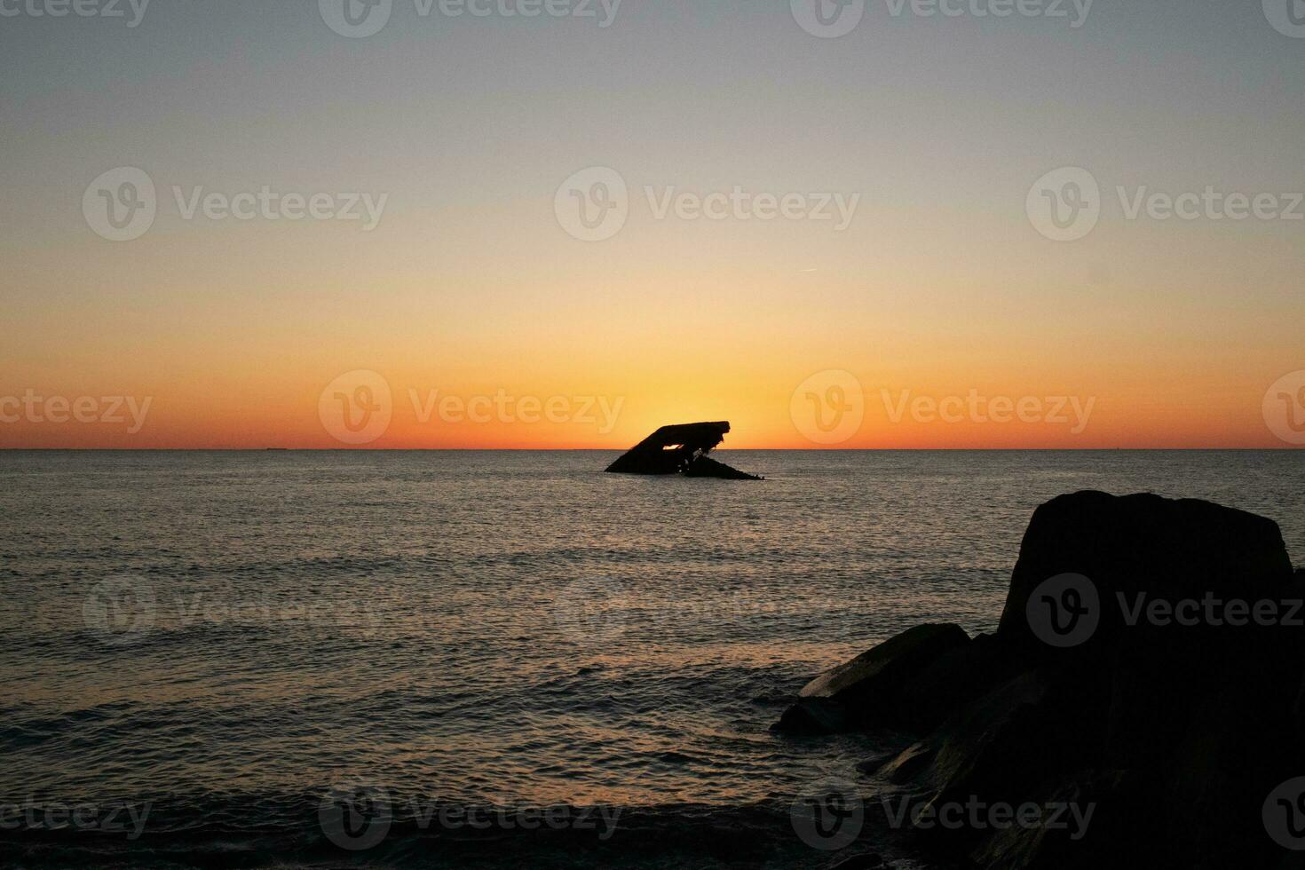 Sunset beach in Cape May New Jersey where you can get a great view of the sun going down across the ocean and the bay. The reflection of the sun on the water with the sunken ship looks so beautiful. photo