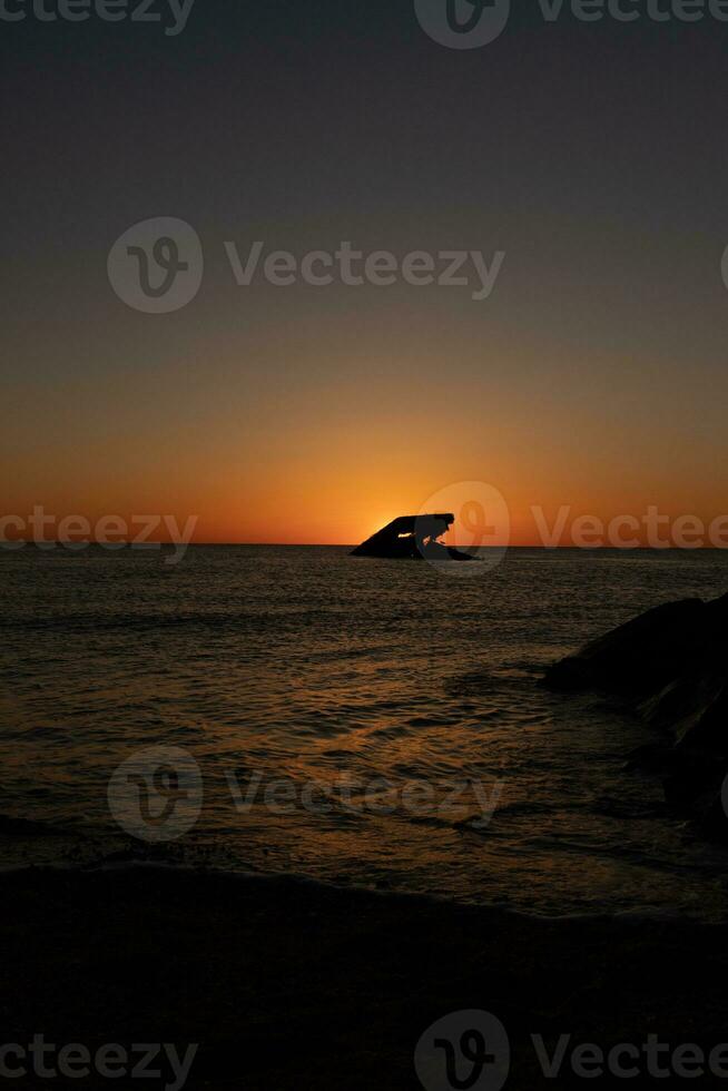 Sunset beach in Cape May New Jersey where you can get a great view of the sun going down across the ocean and the bay. The reflection of the sun on the water with the sunken ship looks so beautiful. photo