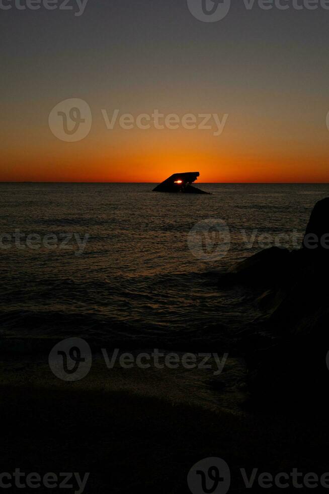 Sunset beach in Cape May New Jersey where you can get a great view of the sun going down across the ocean and the bay. The reflection of the sun on the water with the sunken ship looks so beautiful. photo