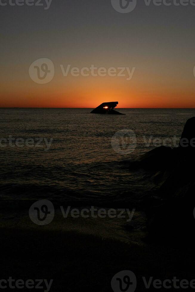 Sunset beach in Cape May New Jersey where you can get a great view of the sun going down across the ocean and the bay. The reflection of the sun on the water with the sunken ship looks so beautiful. photo