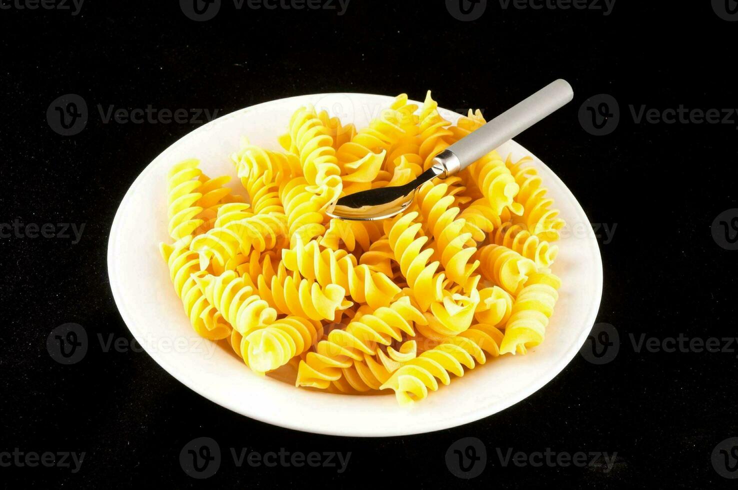 a plate of pasta with a spoon on top photo
