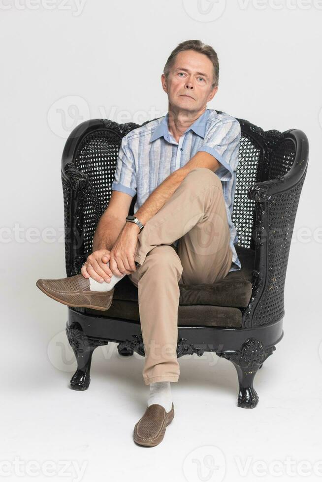 Senior sitting in an armchair and pensive, dreamy photo