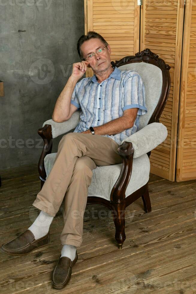 un antiguo inteligente hombre teniendo un descanso en un Sillón foto