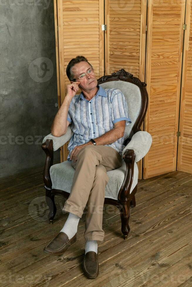 An old intelligent man having a rest on a armchair photo