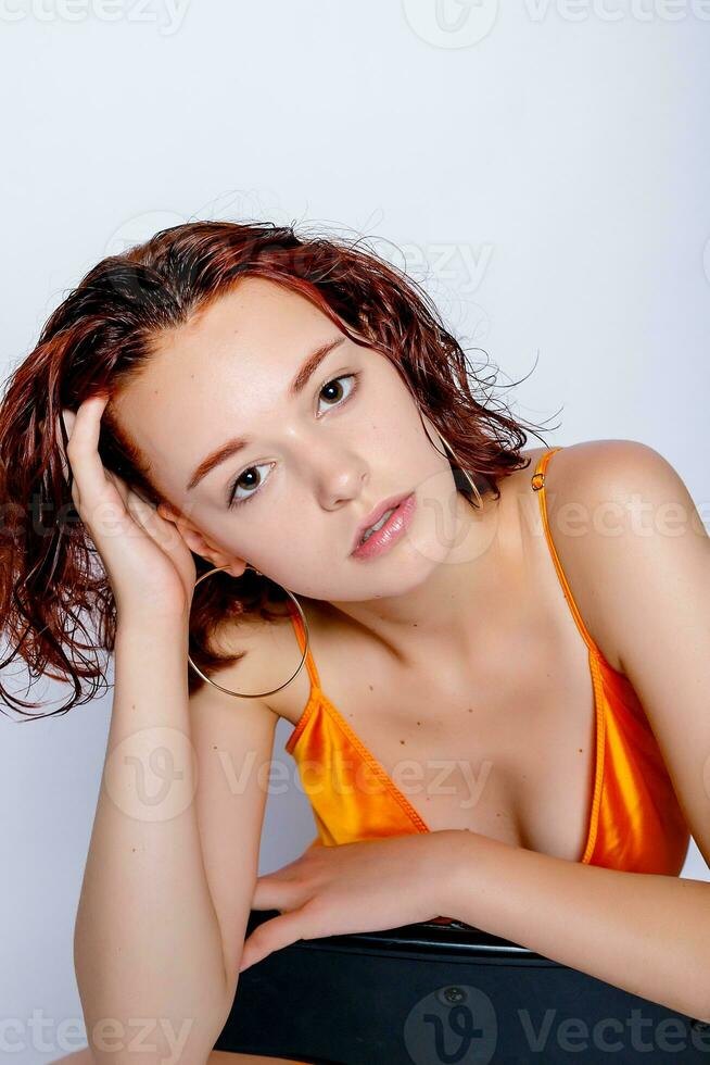 Portrait of attractive girl in orange dress in the studio photo