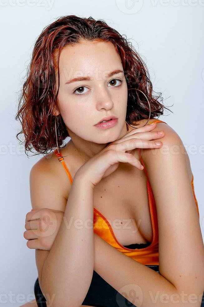 Portrait of attractive girl in orange dress in the studio photo