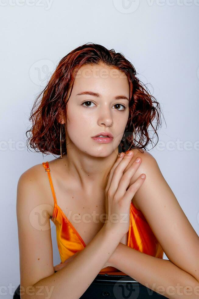 Portrait of attractive girl in orange dress in the studio photo