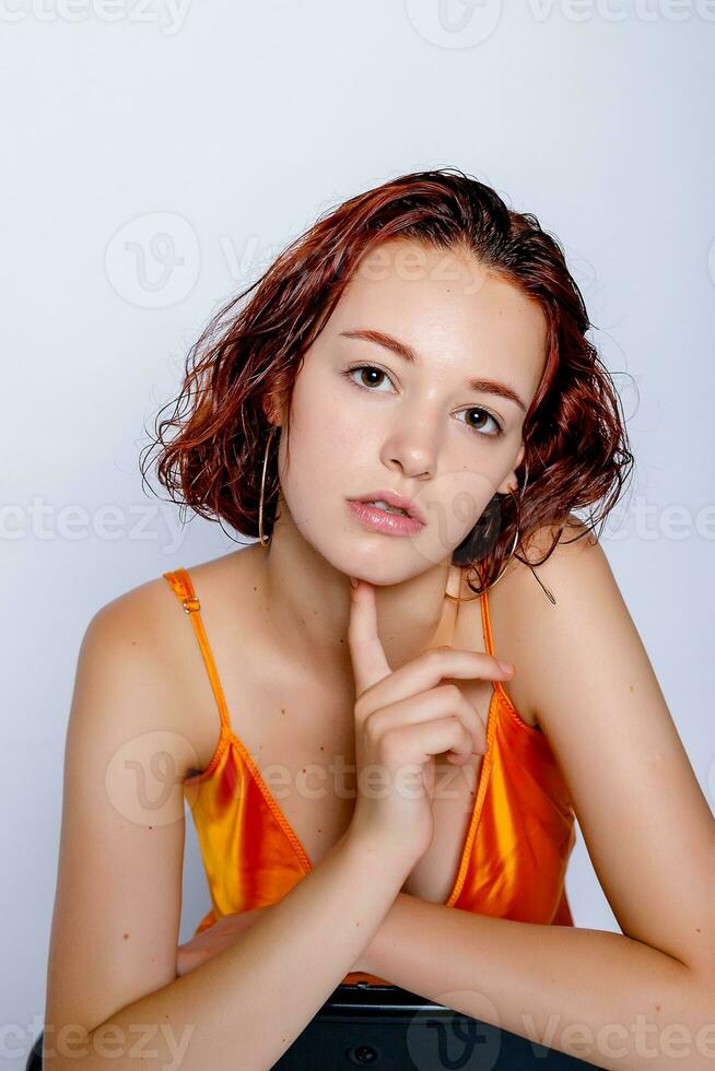 Portrait of attractive girl in orange dress in the studio photo